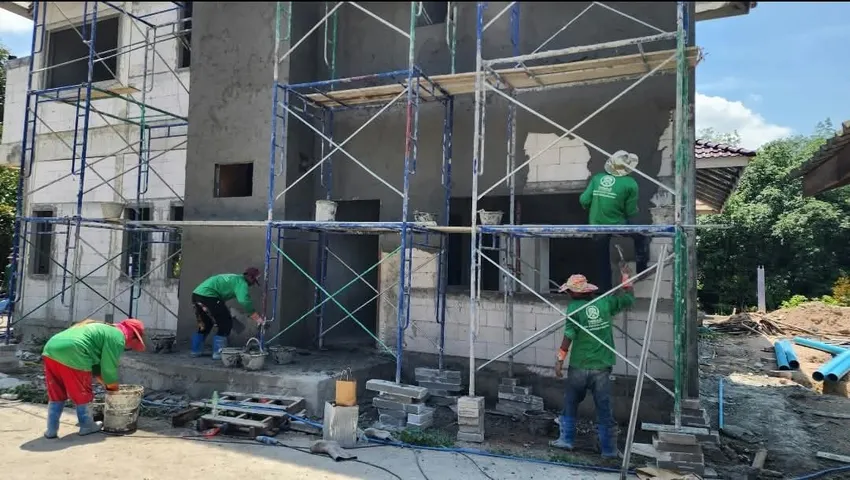 ทีมช่างทำงานบนนั่งร้านระหว่างงานผนังและงานฉาบปูน