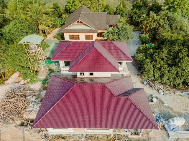 ภาพมุมสูงบ้านหลังใหญ่หลังมุงกระเบื้องหลังคาเสร็จ เห็นแนวหลังคาทรงปั้นหยา